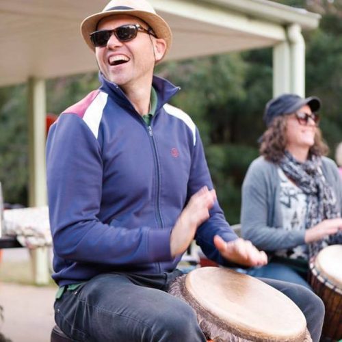 A drummer playing a djembe in the NZ drum camp